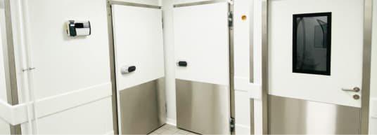 white room with 3 white doors with metal reinforced bottoms