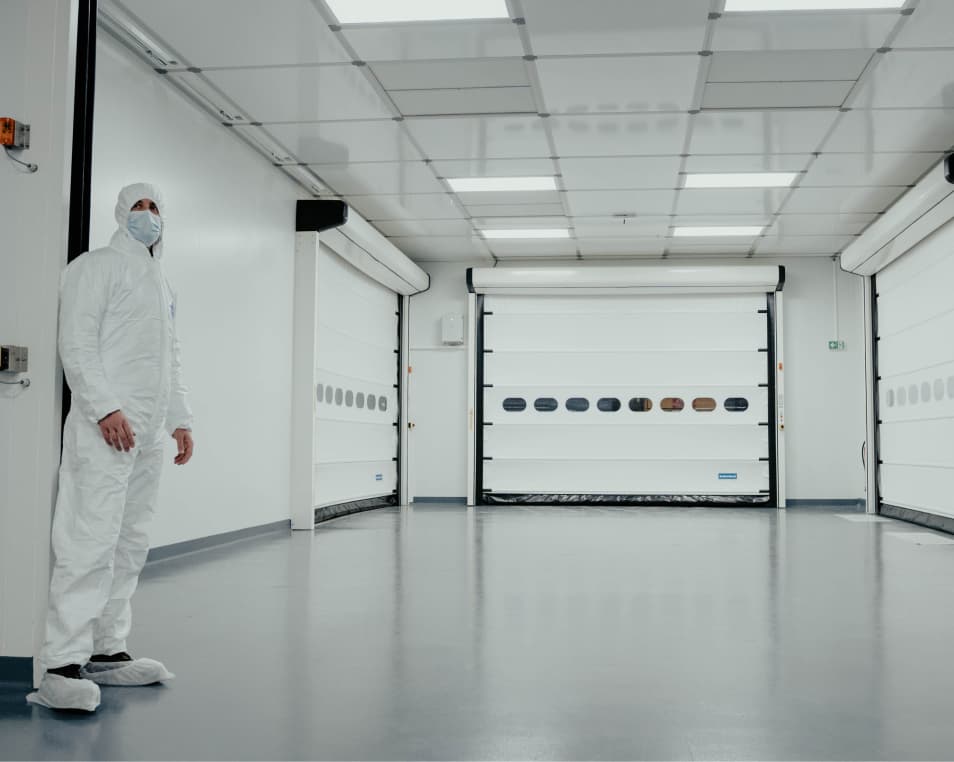 person in hazmat gear standing in a white hallway